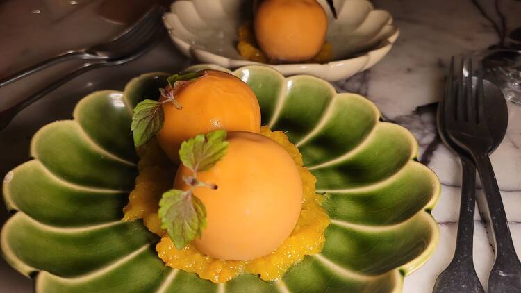 An orange dessert ball on a green plate.