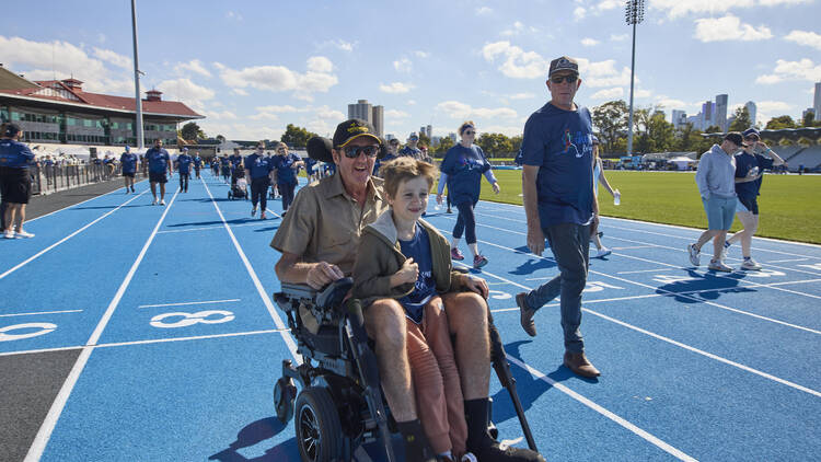 A person in a wheelchair with a child on an athletics track.