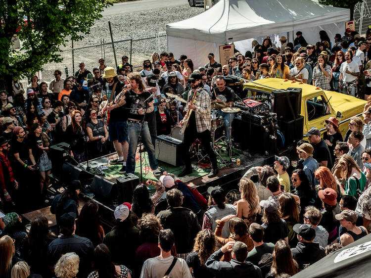 A band playing on the back of a truck in front of a large crowd.