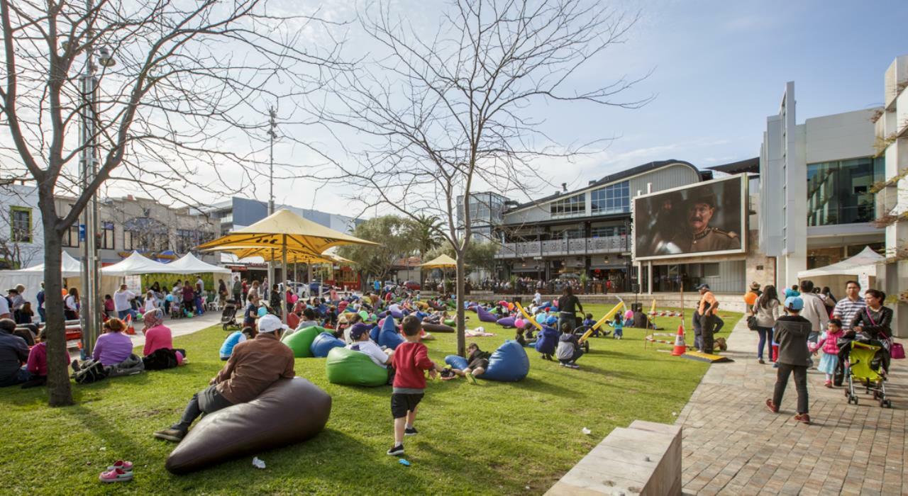 Outdoor lawn with bean bags, people and a big screen TV