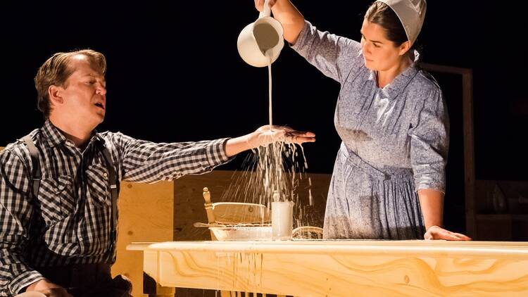 A man holds out his hand while a woman pours liquid onto it.