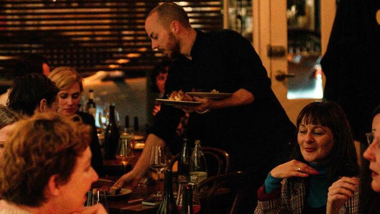 Waiter serving guests at a busy restaurant. 