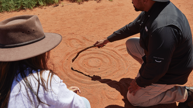 Drawing in sand on Indigenous tour