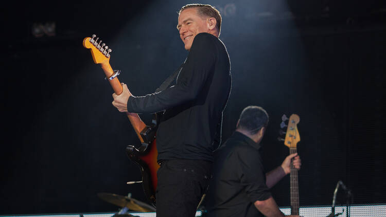 Bryan Adams playing guitar on stage 