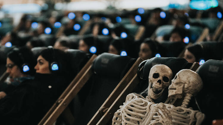 Two skeletons watching a movie.