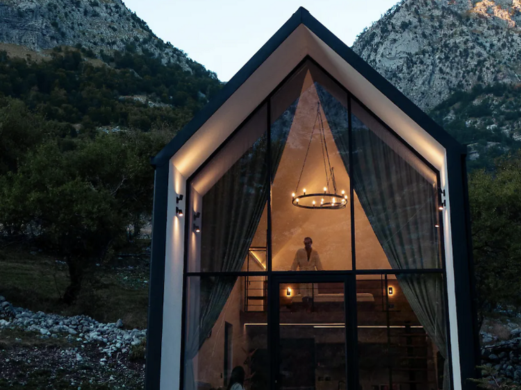 Glass-front cabin with a mountain backdrop.