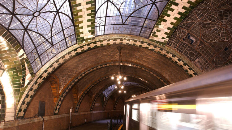 An ornate train station with a train zipping through it.