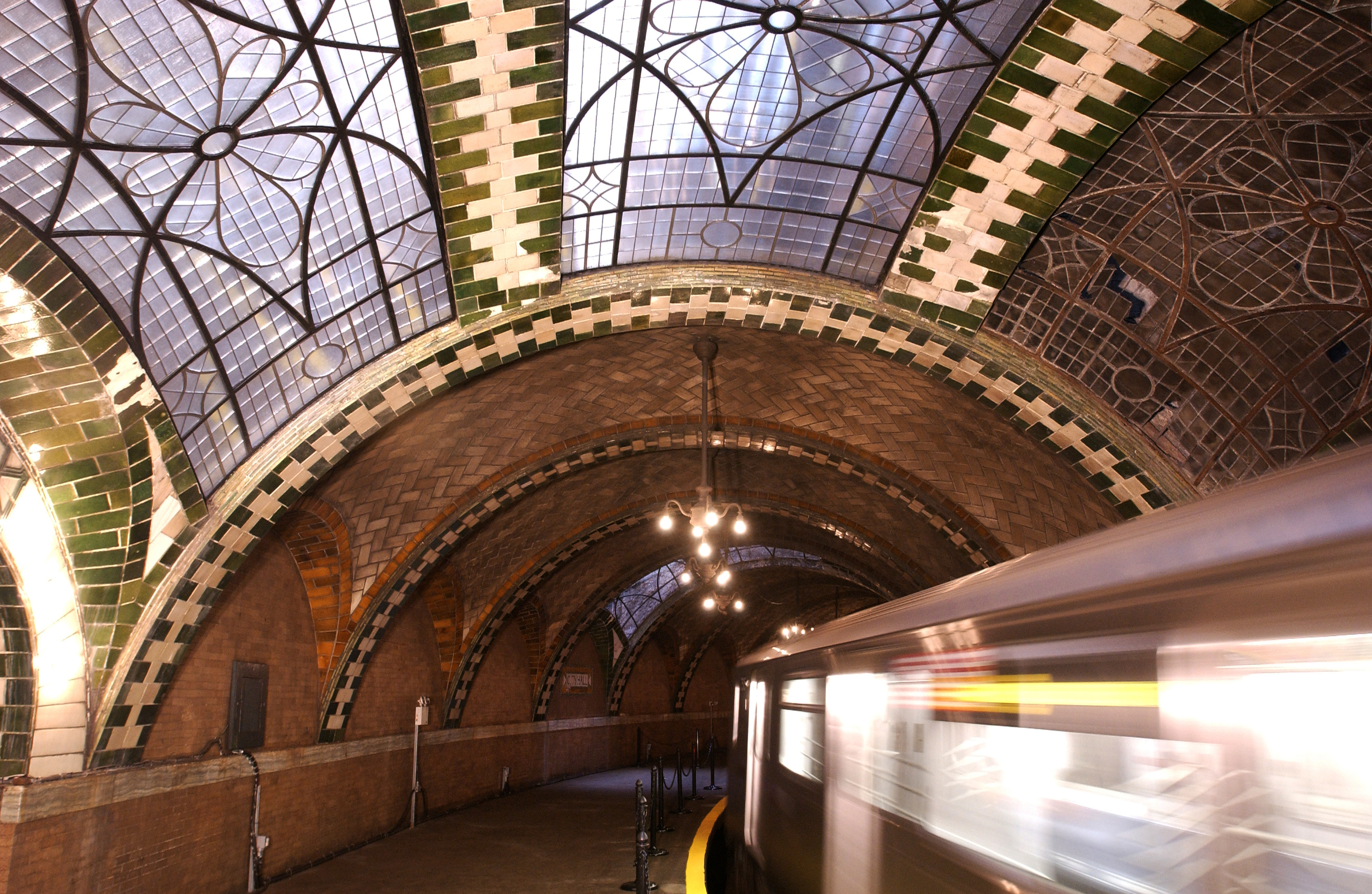 An ornate train station with a train zipping through it.