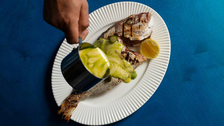 Pouring sauce on a cooked fish 