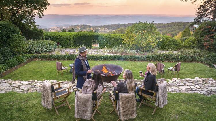 People dining by bonfire in garden at sunset