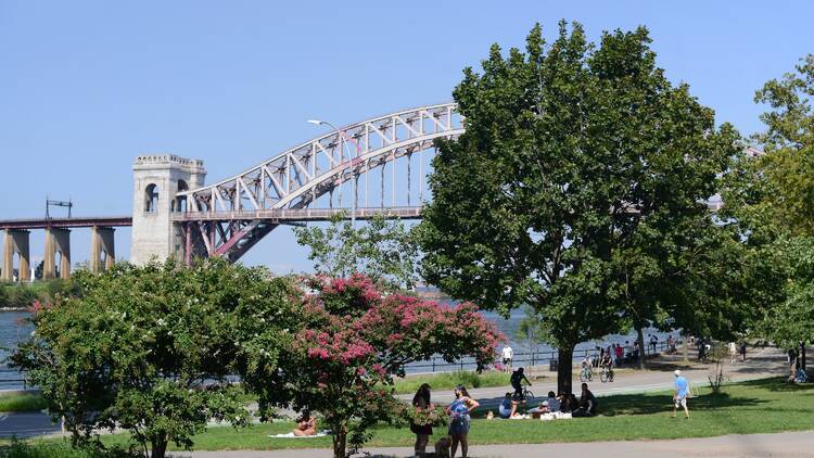 Astoria,NY/USA-Sept 14,2020:Small Pleasures in a COVID World-Part of Astoria Park with a view of the Hell Gate Bridge.People seen picnicking,out with their dogs,riding bikes,and relaxing by the river.