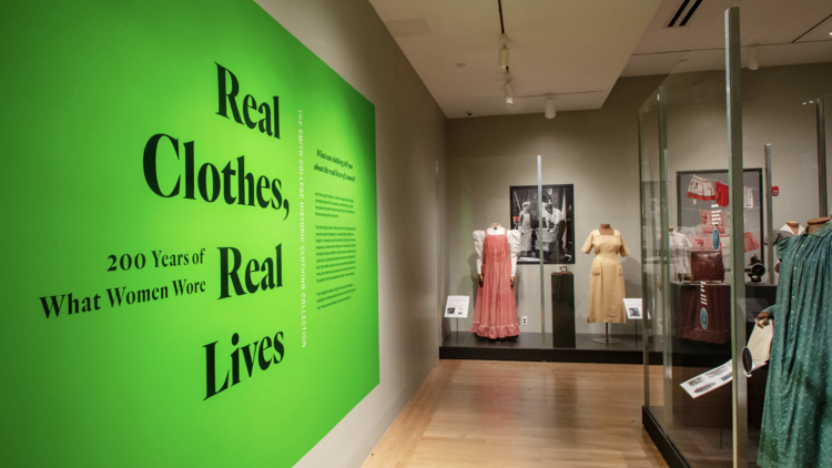 A green sign reading "Real Clothes, Real Lives"