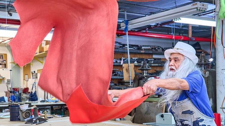 A man unfurls a piece of red fabric in a warehouse at Brooklyn Navy Yard.