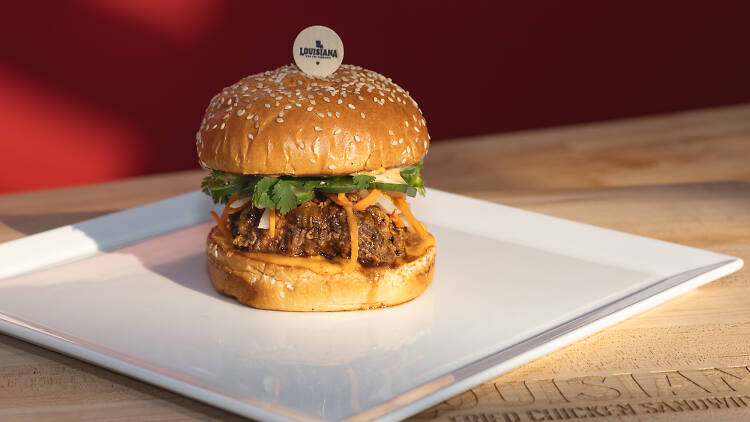 A fried chicken sandwich on a plate with a red background