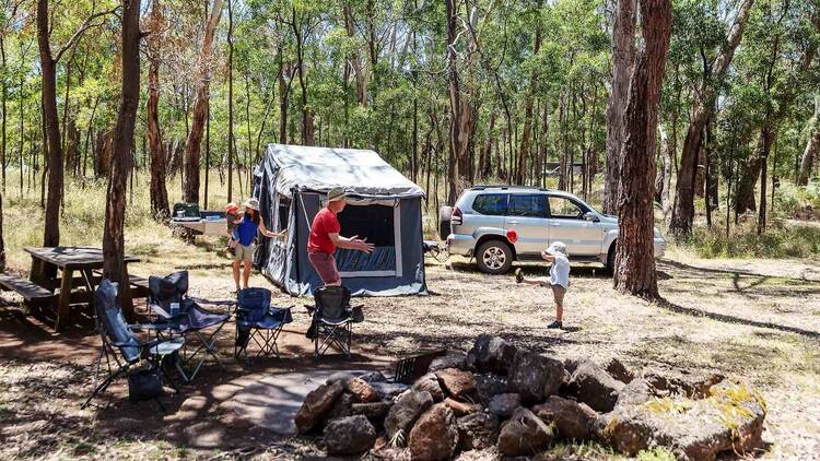 A family at a camp site kicking a ball. 