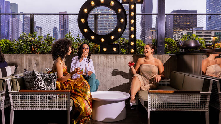 Three people sitting at the QT Rooftop.