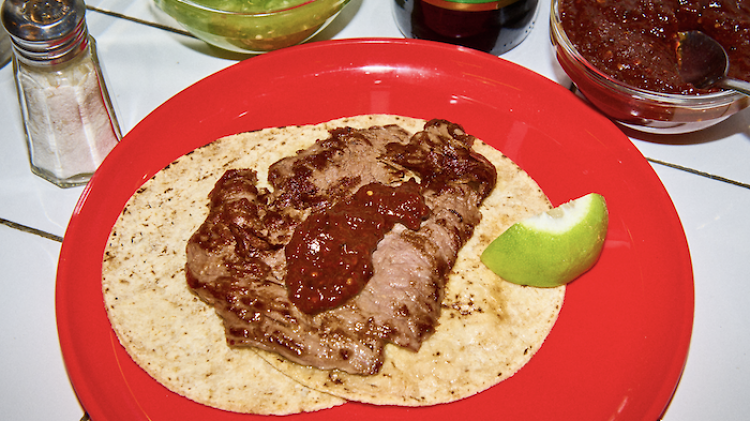 A plate of tacos with thick red salsa on a red plastic plate