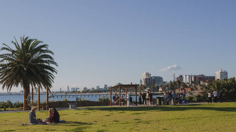 People hanging out on the lawn on a sunny day in St Kilda.