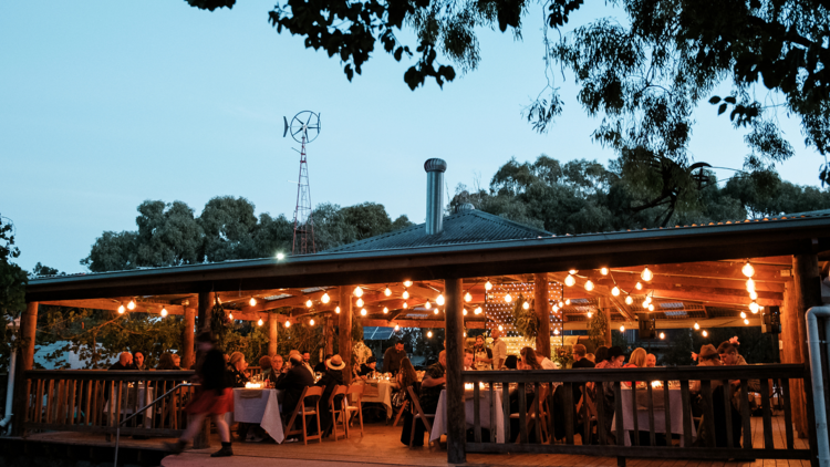 An outdoor restaurant illuminated by strings of light bulbs. 