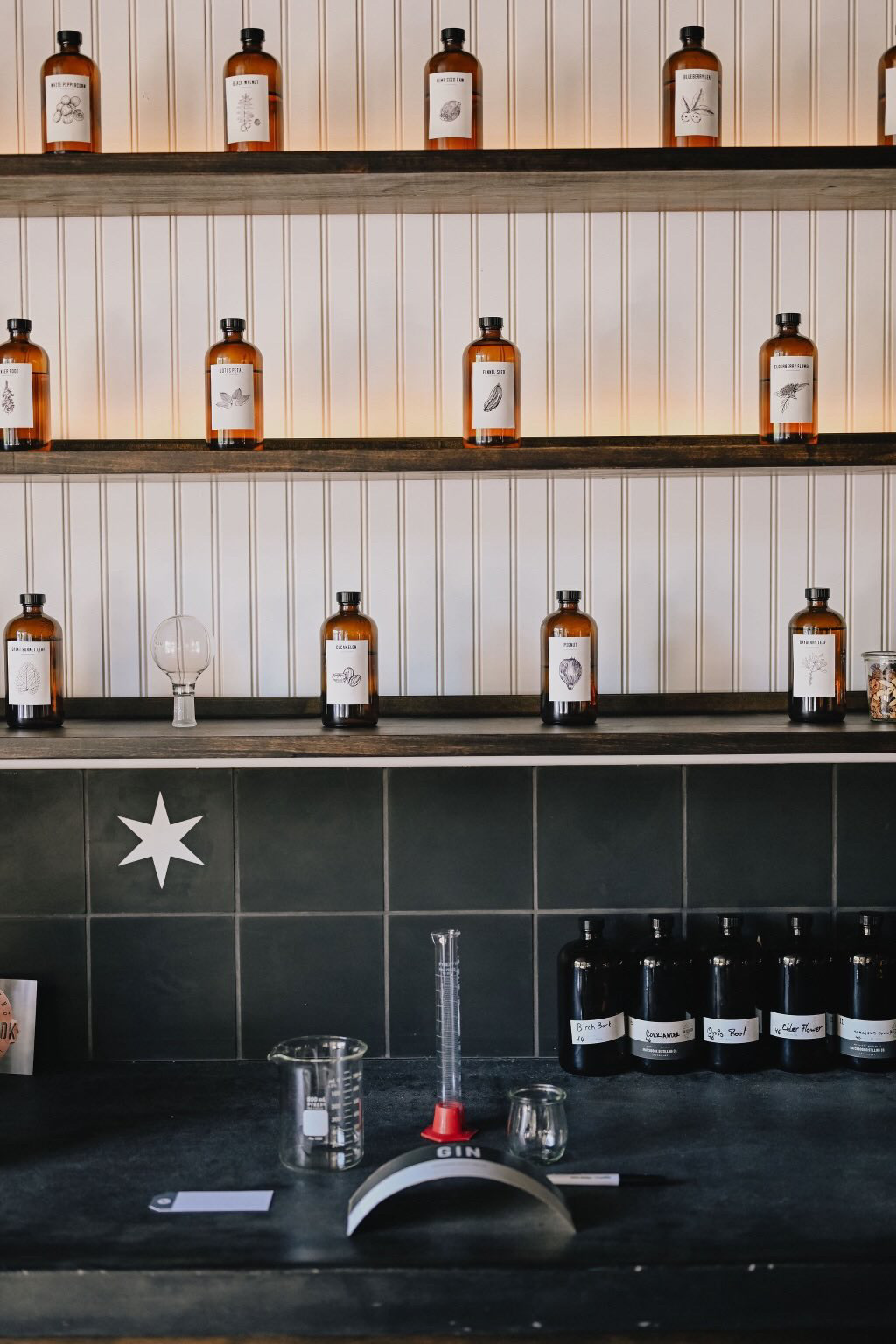 A black granite bar with white walls and brown bottles on the shelves