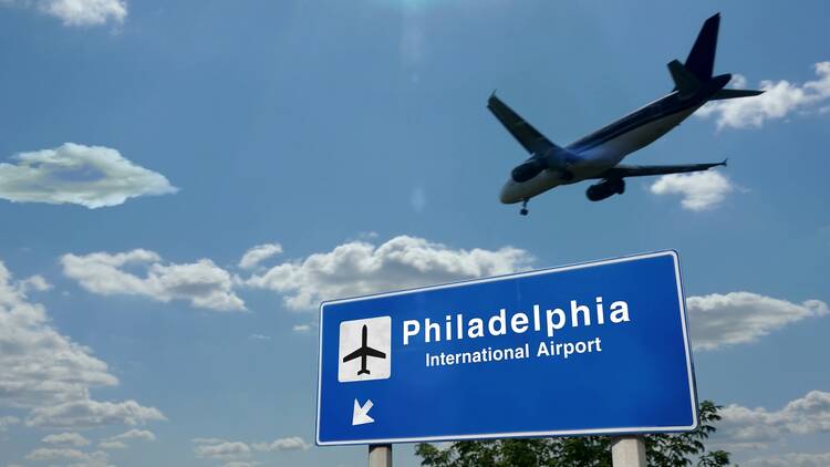 A plane flies above the Philadelphia International Airport.