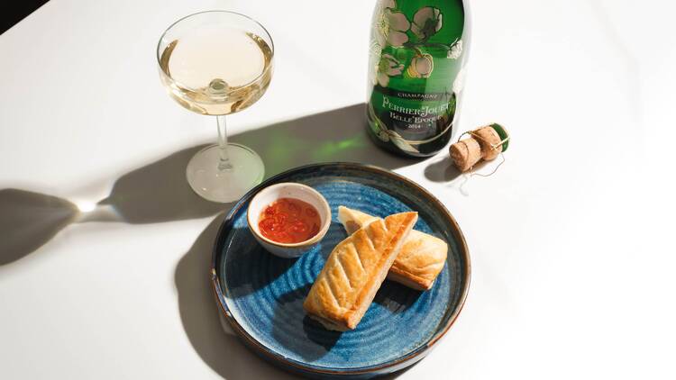 A sausage roll alongside a glass of champagne