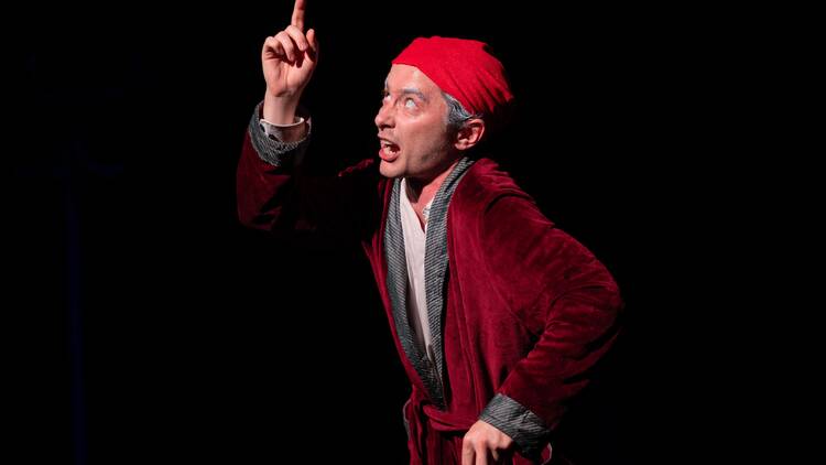 An actor in a red robe and cap portrays Edgar Allan Poe.