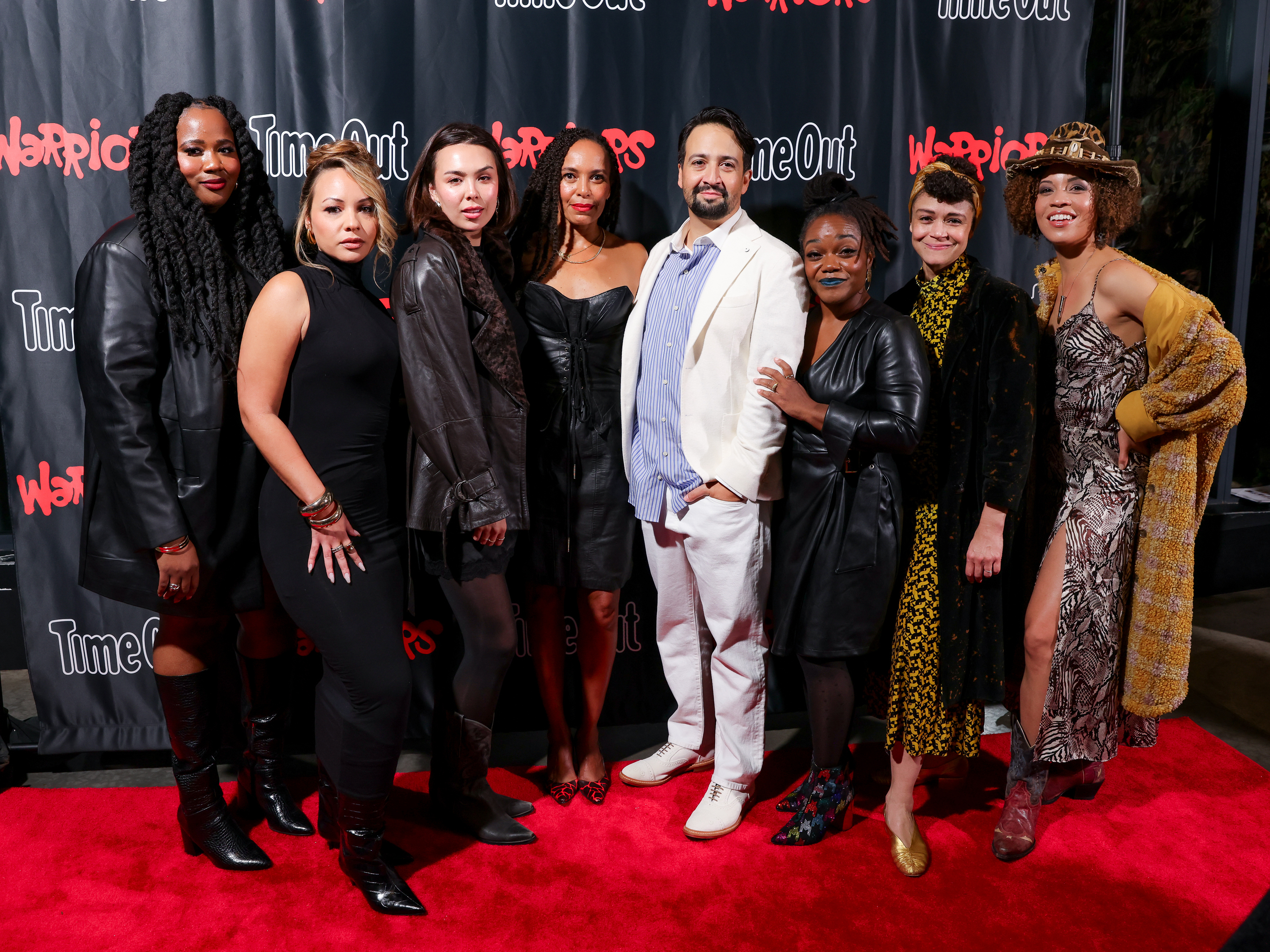 A crowd of people, including Lin-Manuel Miranda, pose on a red carpet.