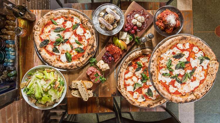 A table ful of pizzas, appetizers and salads