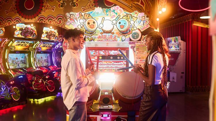 Two adults playing drum arcade games