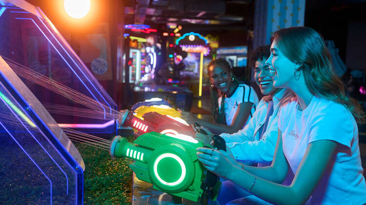 Women playing a laser-style arcade game