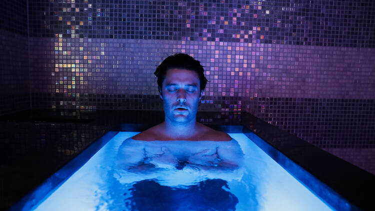 A person meditating in a cold plunge pool.