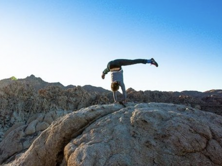 Person performing a handstand on a rock.