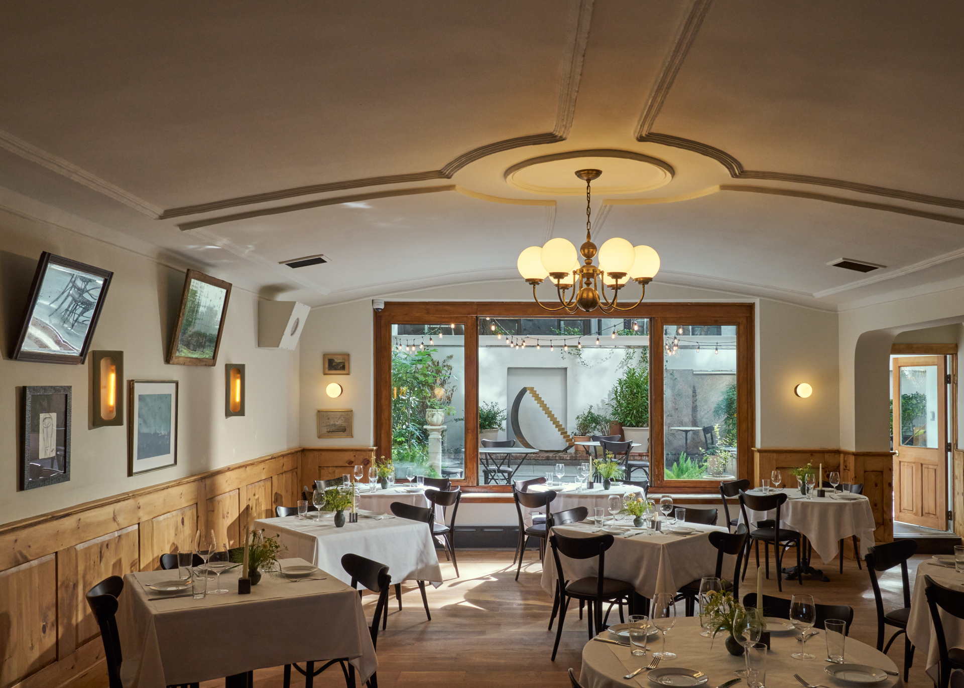 Interior at Borgo with a white curved ceiling, sconce and white table clothed tables