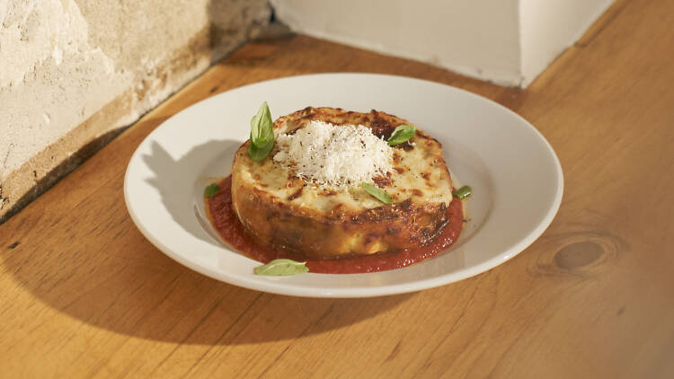 A pasta dish sitting on a white table with a concrete wall in the background