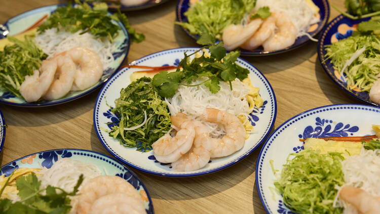 Plates of fresh Vietnamese ingredients, including prawns, rice noodles and vegetables.