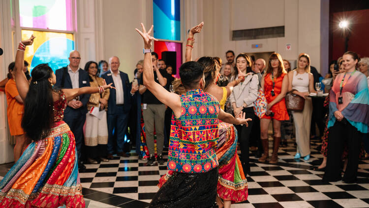 People dressed in colourful cultural clothing performing a dance. 