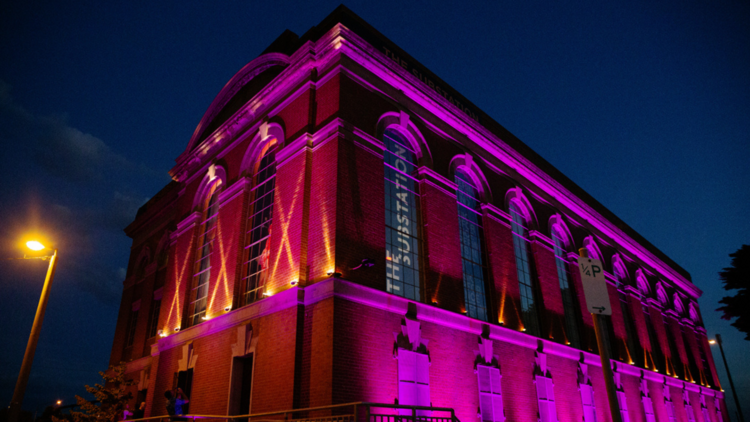 The brick facade of the substation at night illuminated in magenta tones