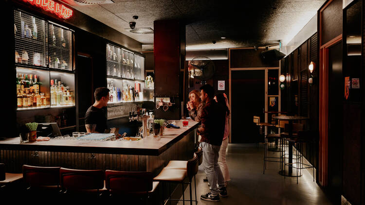 People ordering a drink from a bar. 