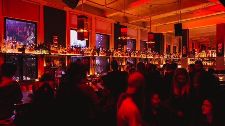 A bar filled with people, with red lighting. 