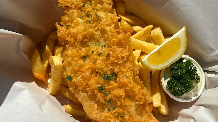 Battered fish and chips with a lemon wedge.