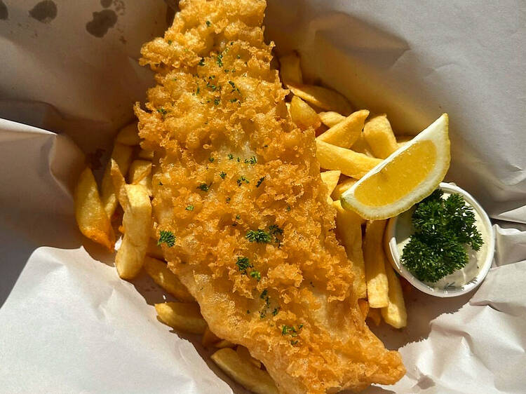 Battered fish and chips with a lemon wedge.