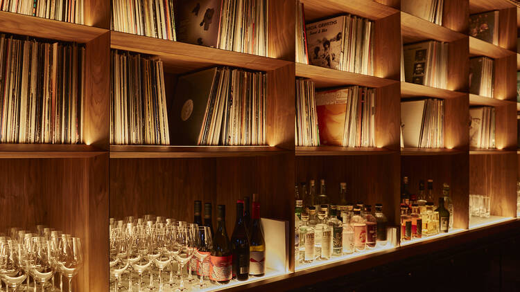 Shelving with rows of records, glassware and liquor. 