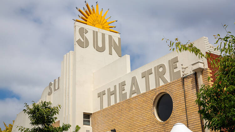 The roof of an Art Deco building with a rising sun on top. 