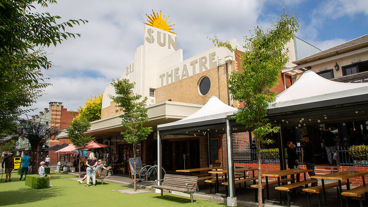 The exterior of a building with tables and chairs outside. 