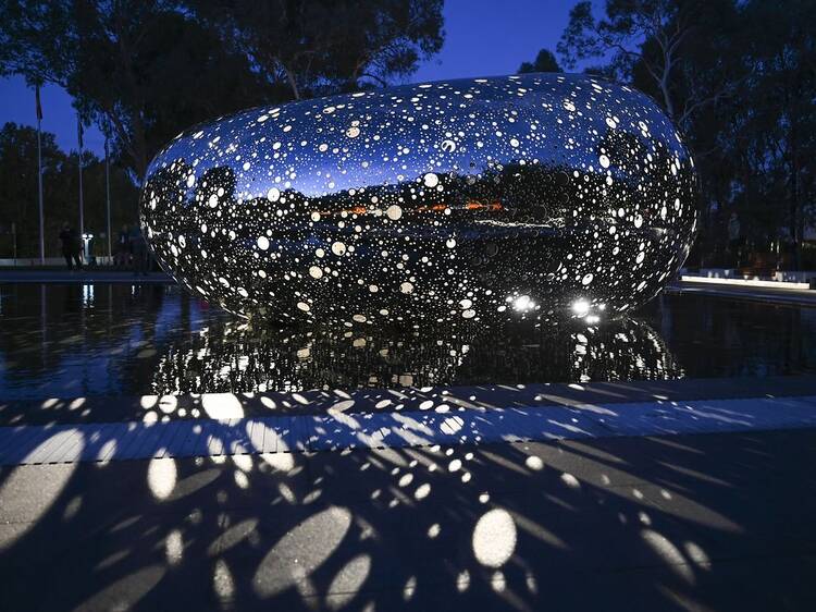 Snake shaped sculpture reflecting lights at night