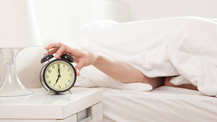 Hand reaching out to turn off alarm clock