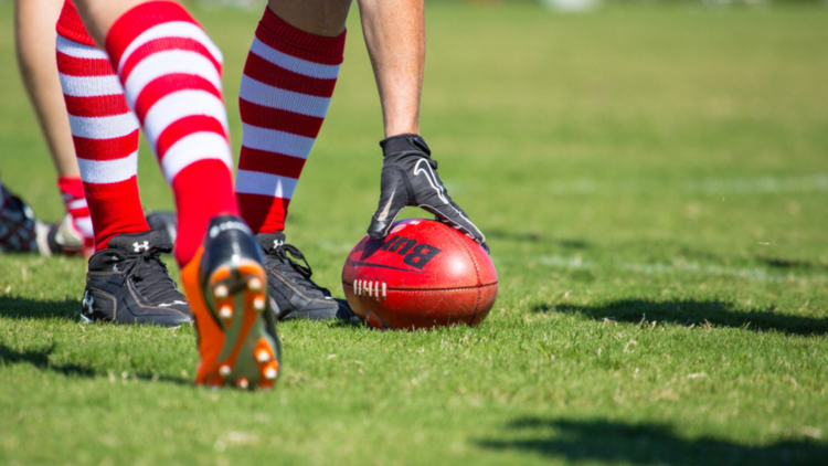 A hand reaches for a football on grass