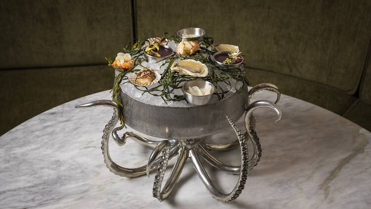 Raw seaffod sitting in a silver platter made to look like an octopus