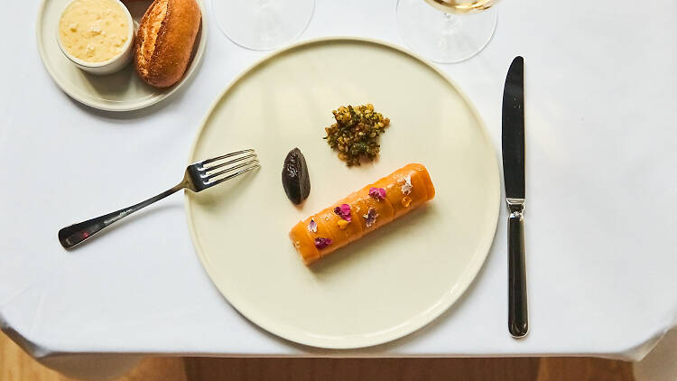 | A white tableclothed table with a plate of rainbow trout and a sourdough bread